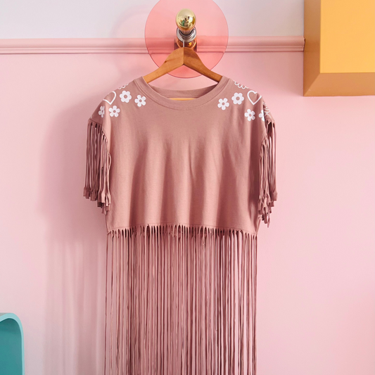 Altrosa Crop-T-Shirt mit Fransen und weißen Blumen- sowie Herzmotiven an den Schultern, hängend auf Holzkleiderbügel vor rosa Wand Nahaufnahme